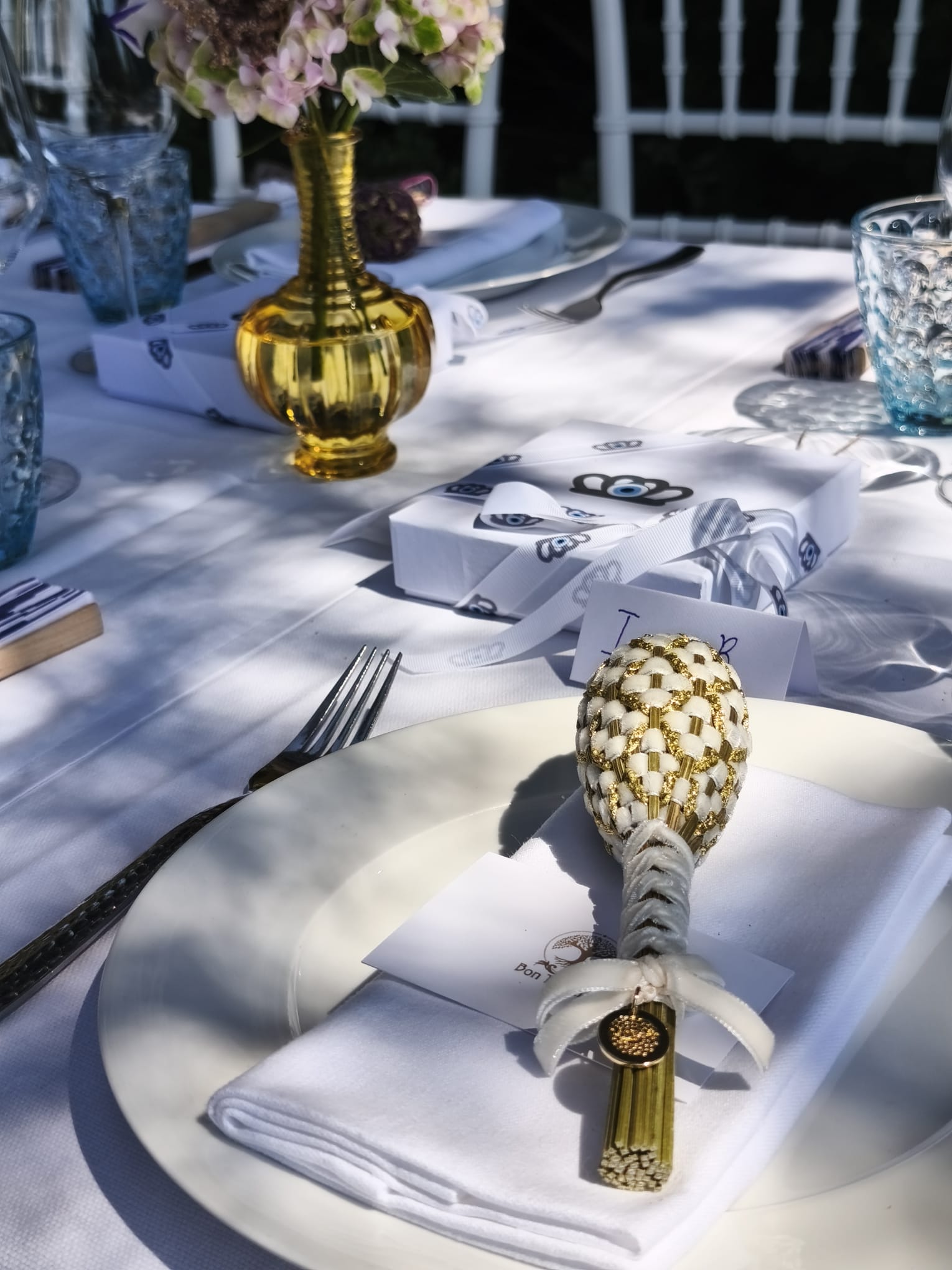 Décoration de table événement haut de gamme avec fuseau Fabergé, serviette blanche, emballage cadeau personnalisé et vaisselle bleue.