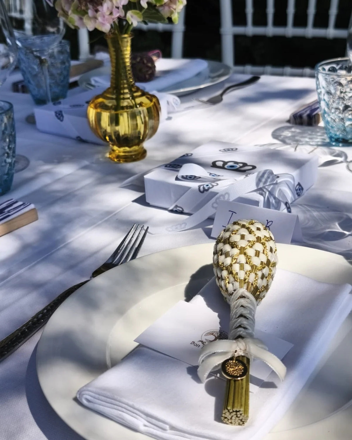 Décoration de table événement haut de gamme avec fuseau Fabergé, serviette blanche, emballage cadeau personnalisé et vaisselle bleue.