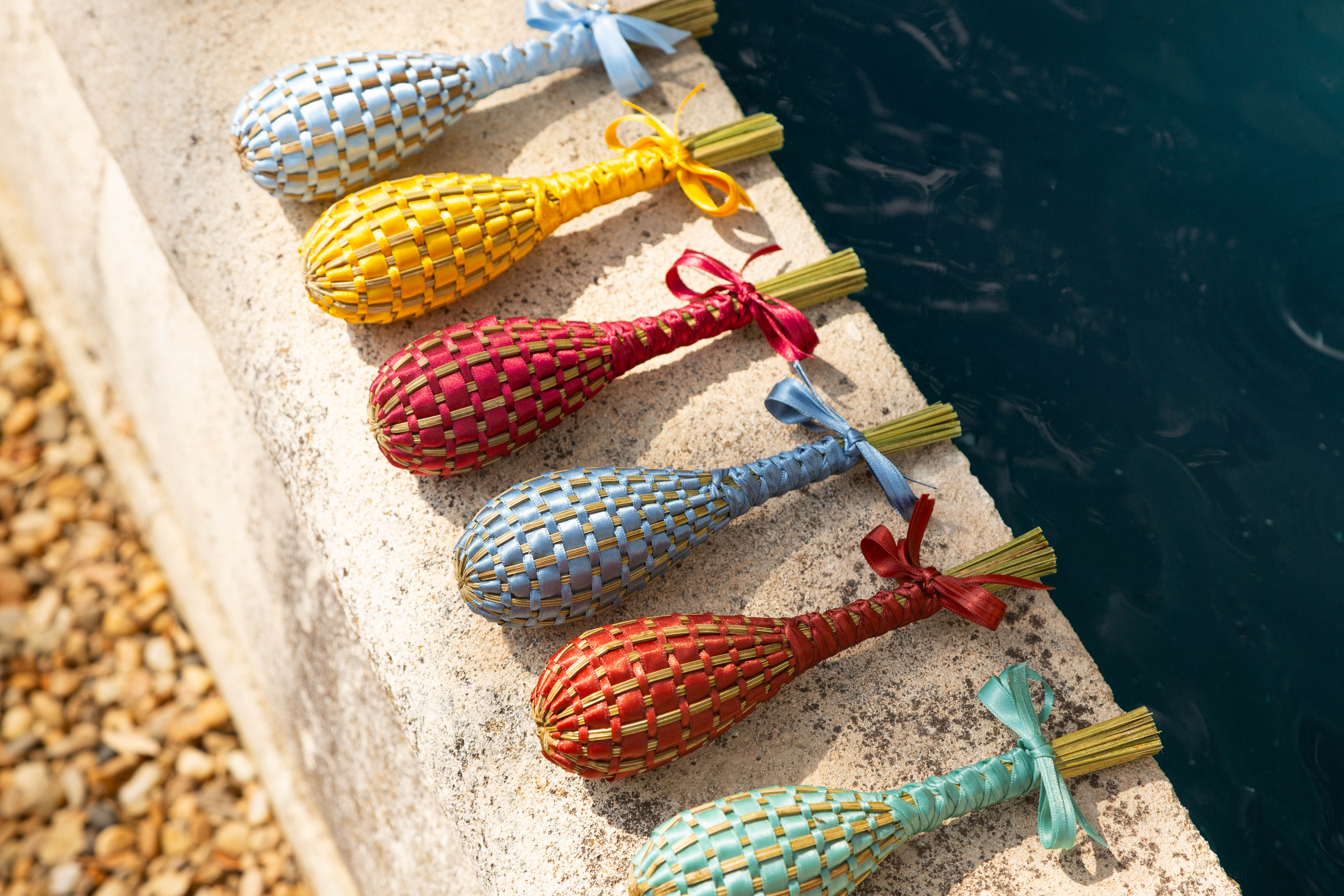 Fuseaux de lavande Franc 1884 mis en scène sur un muret provençal. Chaque fuseau de lavande est tissé avec des rubans de satin signature de Franc 1884.